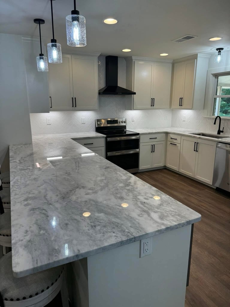 Modern kitchen with white cabinetry, marble countertops, black range, pendant lighting, and stainless steel appliances