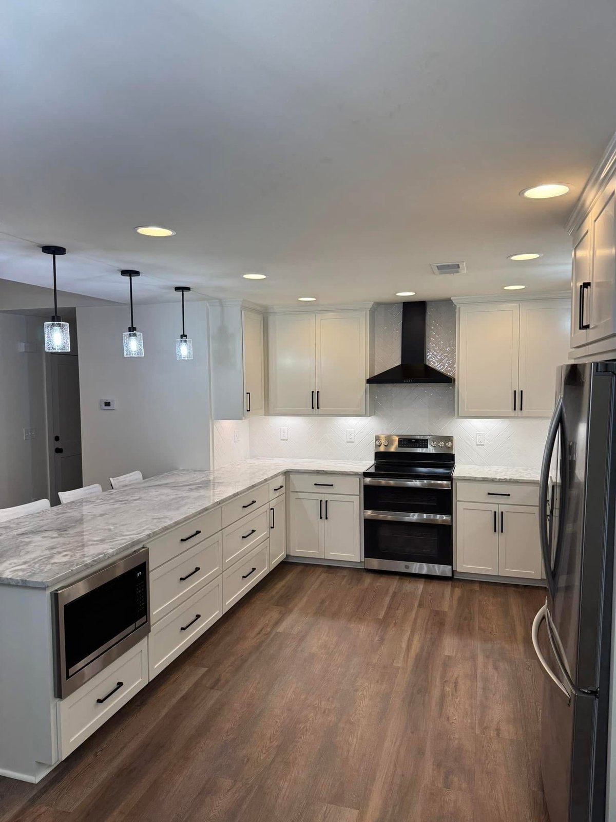 Modern kitchen with white cabinetry, marble countertop, stainless steel appliances, and dark wood flooring